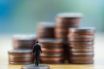 Poster - Close up miniature back businessman standing look up  money stack coin. Business finance growth concept.