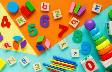 Wall Mural - Wooden kids toys on colourful paper. Educational toys blocks, pyramid, pencils, numbers, train. Toys for kindergarten, preschool or daycare. Copy space for text. Top view	