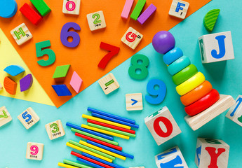 Wall Mural - Wooden kids toys on colourful paper. Educational toys blocks, pyramid, pencils, numbers, train. Toys for  kindergarten, preschool or daycare. Copy space for text. Top view
