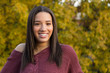 Portrait of mixed raced teenage girl smiling with yellow fall leaves in the background