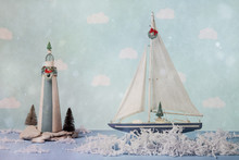 Sailboat And Lighthouse With Shredded Paper Water In A Christmas Holiday Scene