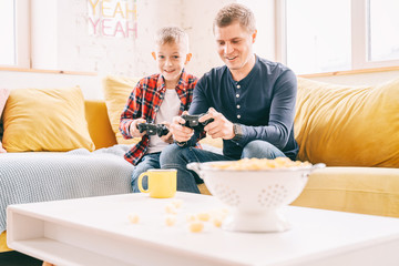 Happy young father and son boy 8 years old play together in a game console, fun and entertainment for the family