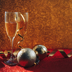 Two glasses of champagne on gold blurred background near christmas balls, gold. Happy new year.