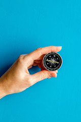 Wall Mural - Choose direction concept. Compass in hand on blue background top view copy space