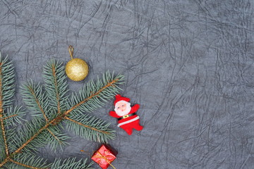 Merry christmas and a happy new year! A sprig of the green symbol of the winter holidays - spruce with decorations on a background of gray artificial leather backing.