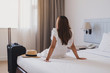 © Kittiphan - Young asian woman traveler with luggage sitting and relaxing on the bed in hotel room