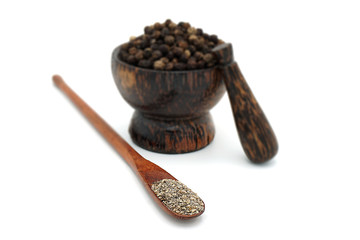 closeup the black pepper in Wooden mortar on white background , selective focus. Herbal Medicines.