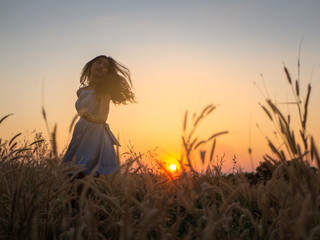 Wall Mural - Trendy girl in stylish summer dress feeling free in the field with flowers in sunshine,enjoying nature, Beautiful Teenage Model in the Spring Field, Sun Light.