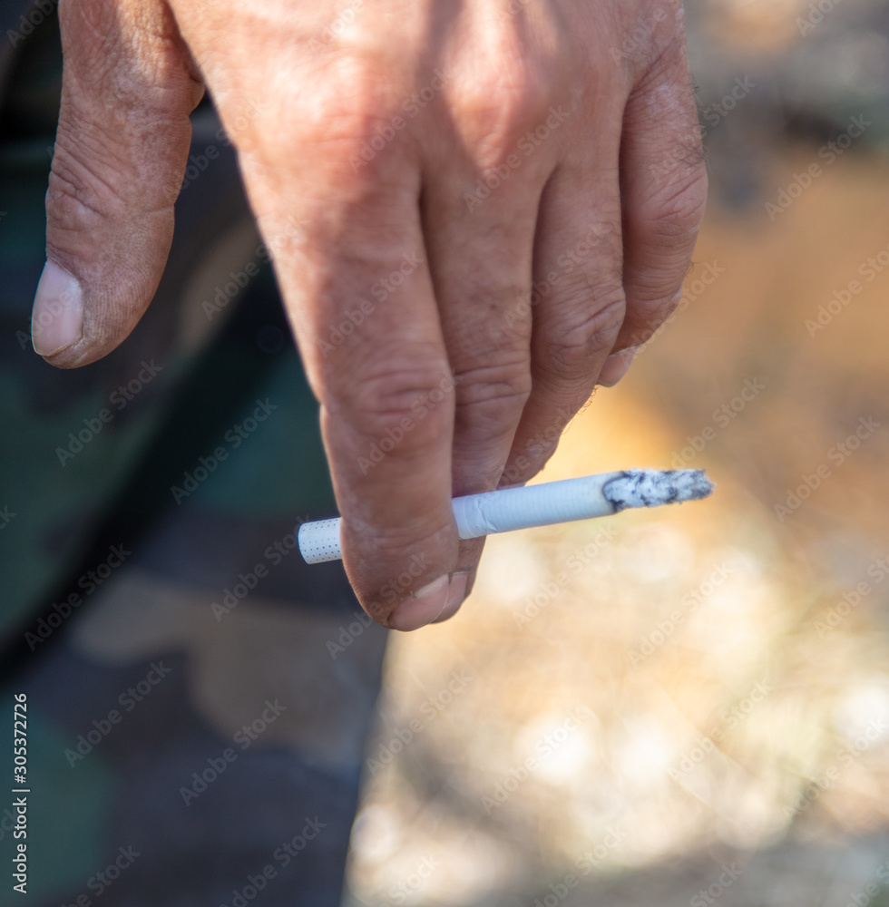 A cigarette burns in a man's hand Stock Photo
