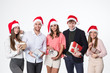 © BestForYou - Group of young beautiful people in santa hats with gifts rejoice on a white.