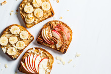 Peanut Butter Toasts With Banana And Apple On A Gray Background, Flat Lay.