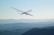 Spy unmanned aerial vehicle (UAV) flies over low mountains in mist