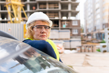 A female builder worker at a construction site works and controls the process.