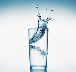 one glass of water with splash from falling ice cube, white background, isolated object