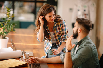 Wall Mural - Colleagues in office. Businesswoman and businessman discussing work in office. Two friends in working together.  