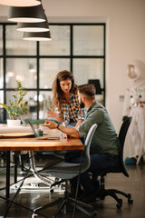 colleagues in office. businesswoman and businessman discussing work in office. two friends in workin