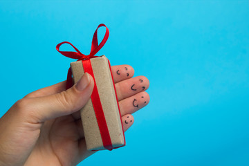 Funny fingers faces present gift box against blue background. Happy family celebrating concept for Christmas or New Years day