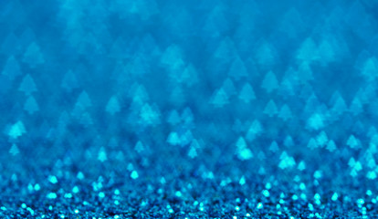 Blue holiday glitter background with Christmas tree bokeh.