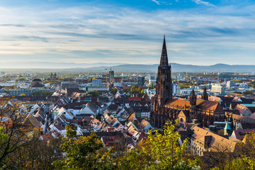 Germany, City freiburg im breisgau skyline with cathedral muenster in old town in warm sunset light in romantic autumn season, aerial view above cityscape