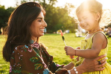 Mother having fun with her little daughter outdoors in nature green park.