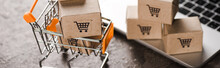Panoramic Shot Of Toy Shopping Cart With Small Carton Boxes Near Laptop, E-commerce Concept