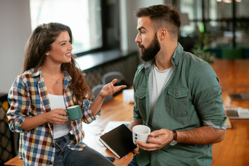 Wall Mural - Colleagues in office. Businesswoman and businessman discussing work in office. Two friends in working together.