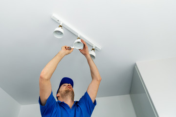 electrician installing led light bulbs in ceiling lamp