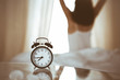 © rogerphoto - Woman stretching hands in bed after wake up, sun flare . Brunette entering a day happy and relaxed after good night sleep and back view. Concept of a new day and joyful weekend