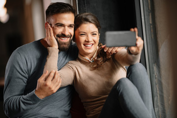 Wall Mural - Happy couple taking selfie. Girlfriend and boyfriend together having fun. Happy couple.