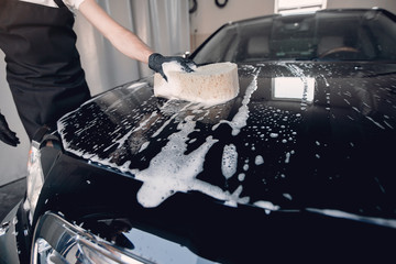 Man in a garage. Worker washing a car.