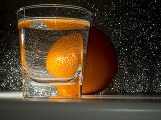 Reflection of an orange in a glass of water with bubbles.