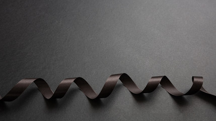 Wall Mural - black ribbon curl on black color background. minimal black card template