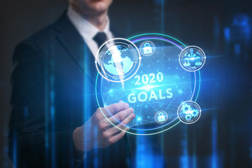 Business, Technology, Internet and network concept. Young businessman working on a virtual screen of the future and sees the inscription: 2020 goals