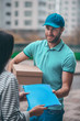 © zinkevych - Handsome bearded delivery man passing parcel to his client