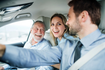 Wall Mural - Young couple with senior father sitting in car, driving and talking.