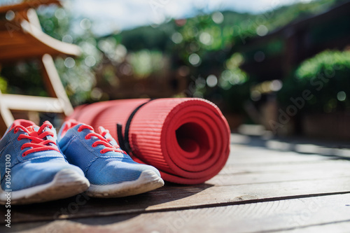 Fotomural Exercise mat and trainers outdoors on a terrace in summer.