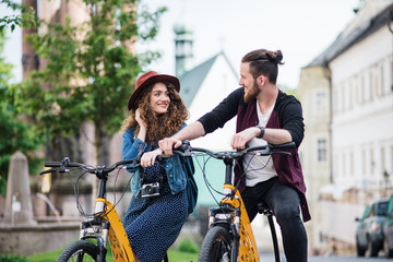 Wall Mural - young tourist couple travellers with electric scooters in small town.