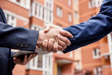 Colleagues handshaking before office building outdoors close up