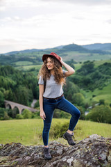 Wall Mural - young tourist woman hiker with backpack standing in nature, resting.