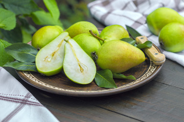 fresh pears and pear halves in a plate on the table. background with green fresh pears closeup.