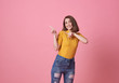 Happy young woman standing with her finger pointing isolated over pink banner background with copy space.