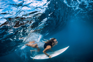 Surfer make duck dive underwater. Surfgirl dive under wave