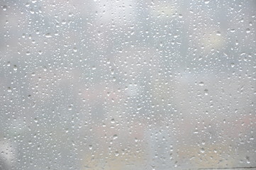 Window with rain droplets and grey sky in background