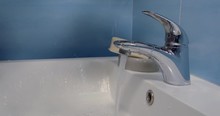 Close - Up Of The Tap With Running Water Over The White Sink In The Bathroom With Blue Tiles On The Wall. The Man Takes Water In Handfuls, Picks Them Up, Takes Soap, Soaps His Hands