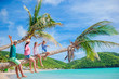 © travnikovstudio - Happy family on the beach on palm tree during summer vacation