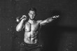 © Srdjan - Young strong sweaty focused fit muscular man with big muscles holding heavy kettle bell on his shoulder for training hard core cross workout in the gym real people black and white