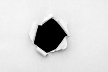 A Round Hole In White Paper With Torn Edges And A Black Isolated Background Inside.