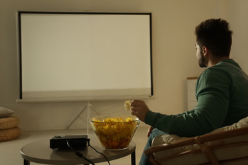 Canvas Print - Young man watching movie using video projector at home