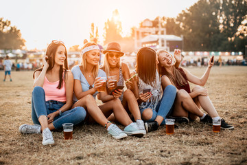 Female friends having fun and using phones at music festival