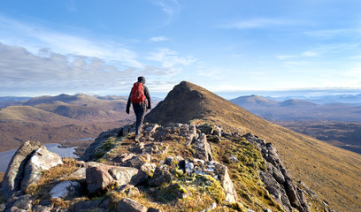 a hiker walking towards the summit of sgurr an tuill bhain along a narrow rocky ridge in the scottis